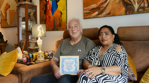 Mevrouw en meneer zittend op de bank met een tegeltje in de hand