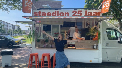 Een medewerkers van Staedion nodigt bewoners uit om naar de traktatiebus te komen