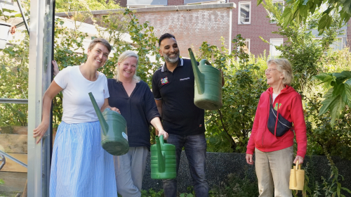 Vier mensen lachend, aan het werk in de tuin met hun gietsers