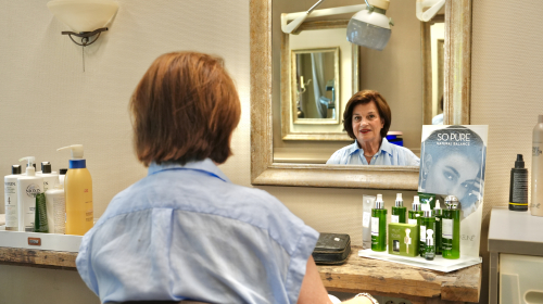 Een dame in haar kapsalon in de spiegel