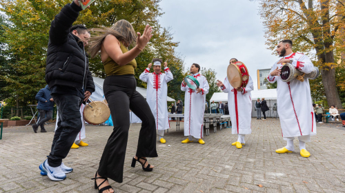 Een koppel staat druk te dansen naast mannen die muziek maken