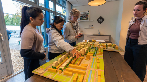 Een groepje staat te kijken naar een maquette van de wijk