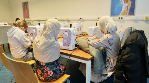 Drie meisjes krijgen naailes bij de Lichtpuntjes