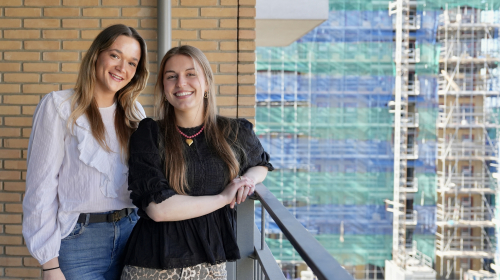 Twee dames poseren op een balkon voor woningen die gebouwd worden