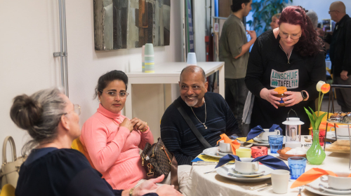 Bewoners aan tafel en met elkaar in gesprek tijdens de feestmaaltijd op 9 maart