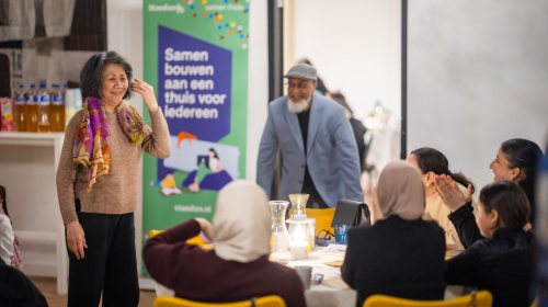 Bewoners met elkaar in gesprek tijdens de feestmaaltijd op 9 maart