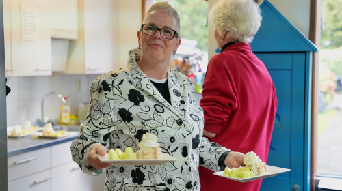 Lydia in de Buurtkamer met taart in haar handen.
