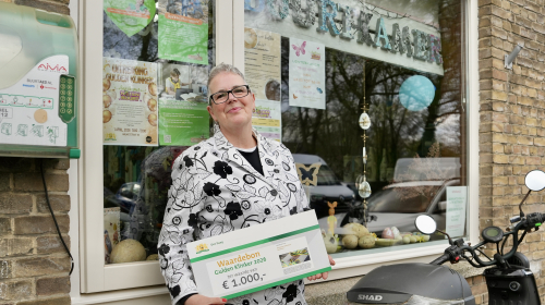 Lydia poseert voor haar Buurtkamer met de cheque van de Gulden Klinker.