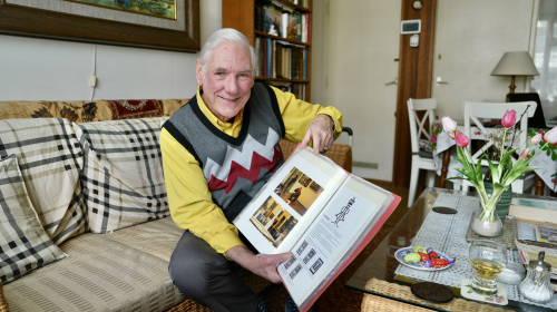Pim in zijn woonkamer op de bank met een fotoalbum in zijn handen