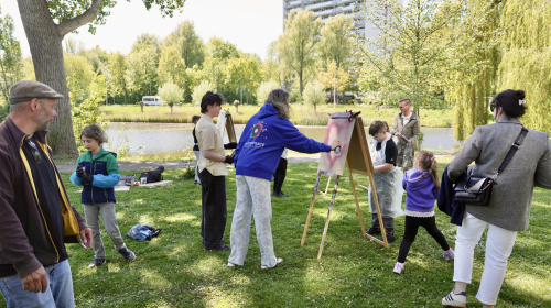 De kunstenaar begeleidt een groep mensen in het schilderen op doek