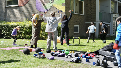 Een aantal mensen sporten met gewichten in de tuin van het gebouw