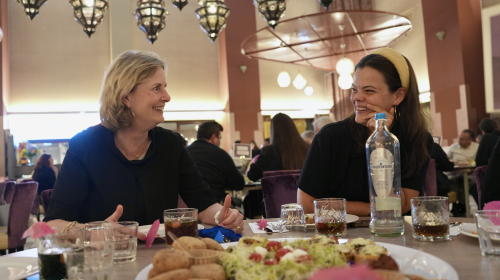 Twee lachende dames aan tafel met hapjes