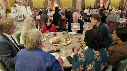 Een groep mensen aan een ronde tafel, in gesprek over vrede