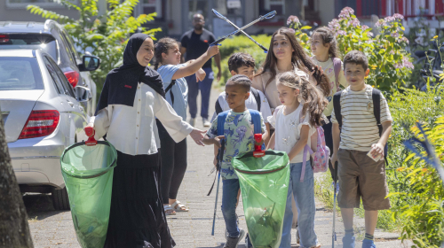 Kinderen met een mevrouw afval aan het opruimen