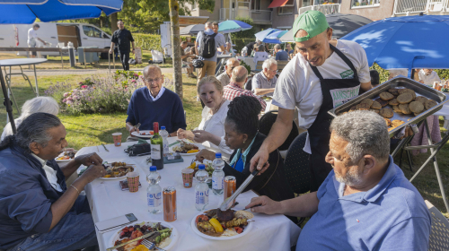 Bewoners genieten van het lekkere eten bij de bbq bij woongebouw Landzicht
