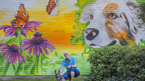 Margriet met haar hond voor de muurschildering