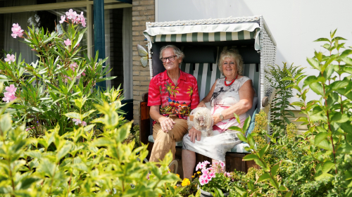 Cas en Carla met hond op schoot in de strandstoel in hun tuin