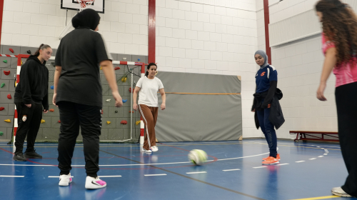 Vijf meisjes aan het voetballen in een sporthal