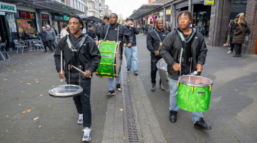 Mannen slaan op trommels om aandacht te vragen voor het evenement van Buurt-Genoten