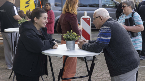 Bewoners praten met elkaar aan een statafel