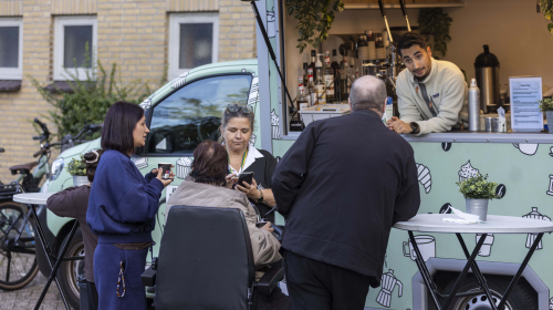 Bewoners praten met elkaar met op de achtergrond de koffiekar