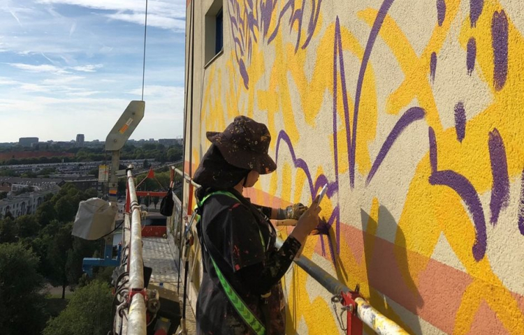 Kunstenaar Gleo is aan het werk aan de muurschildering
