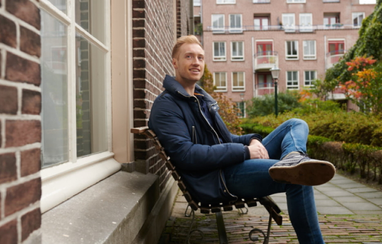 Kars zittend op een bankje voor een woning