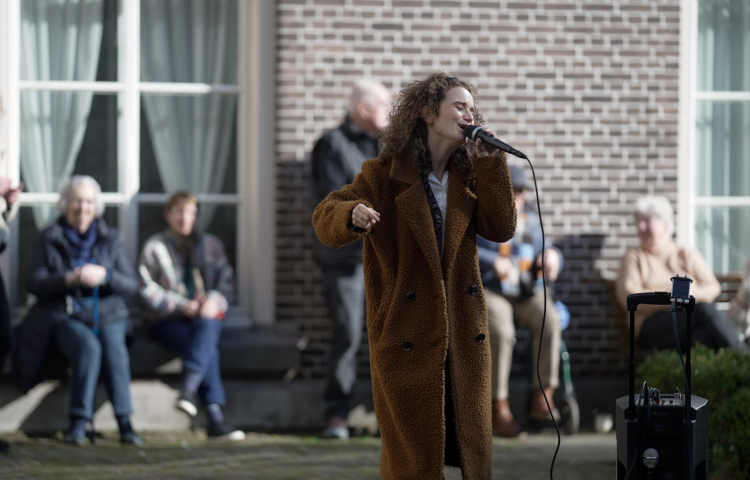 Zangeres zingend op een plein met kijkende mensen
