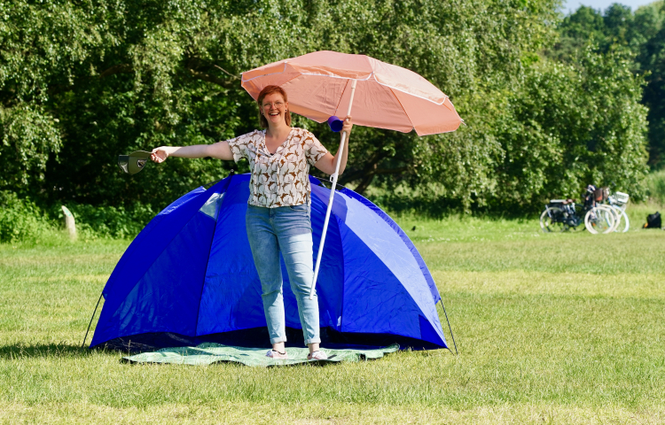 Killian voor een tent met een parasol op de Buurtcamping zuiderpark 