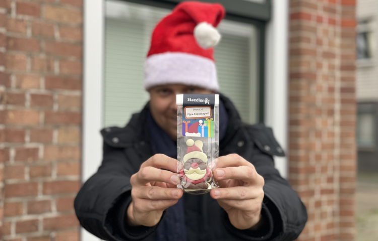 Medewerker van Staedion met kerstmuts op laat de kerstkransjes zien
