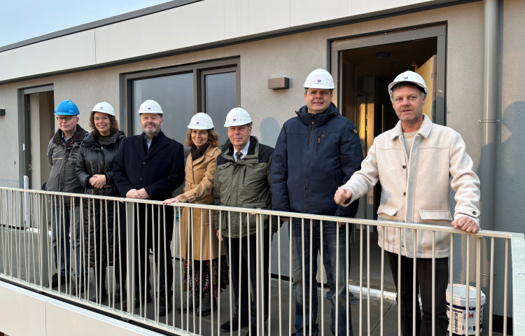 Groepsfoto van de deelnemers van de prestatieafspraken op een galerij met een helm op
