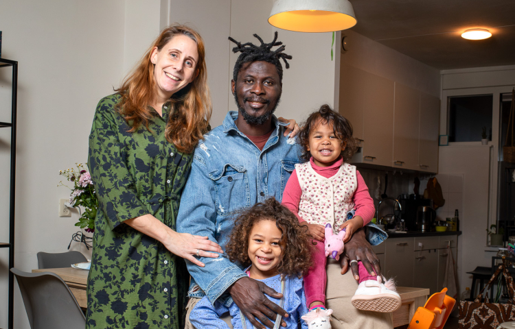 Gezin van vier personen. Vrouw, man en twee meisjes poseren in de woonkamer.