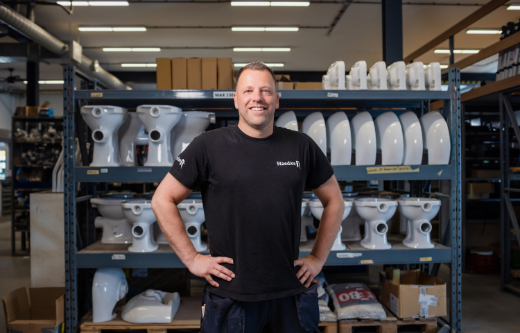 Man staat trots voor een stelling met bouwmateriaal.