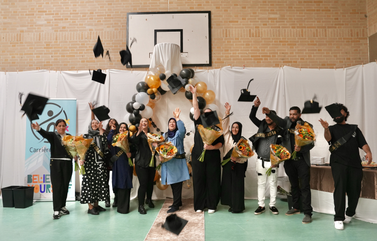 Een groep dames en heren gooien hun geslaagd hoedje in de lucht, ook houden ze bloemen vast