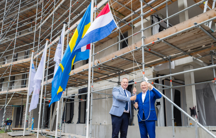 Twee mannen hijsen de Nederlandse vlag