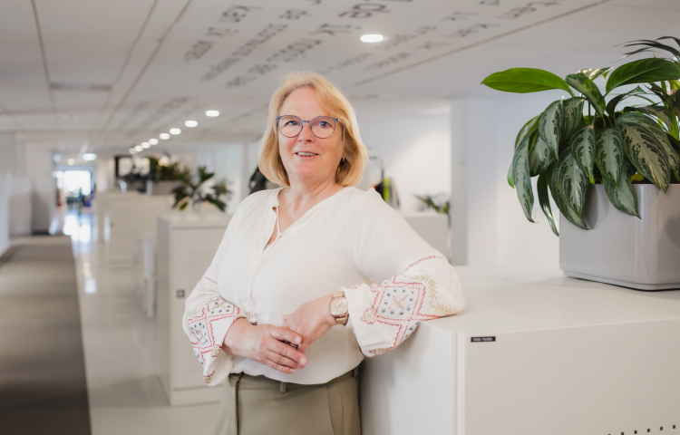 Mevrouw met handen over elkaar, leunt tegen kast