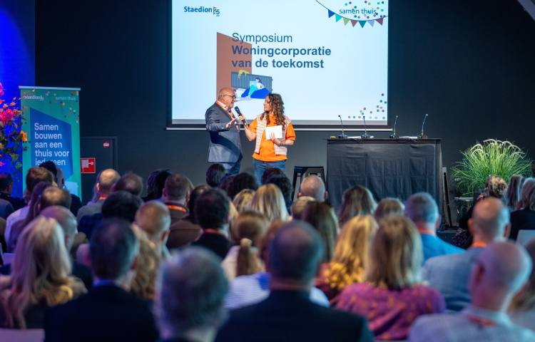 Jacques Thielen en dagvoorzitter Jessica Mendels op het podium bij het symposium Woningcorporatie van de toekomst