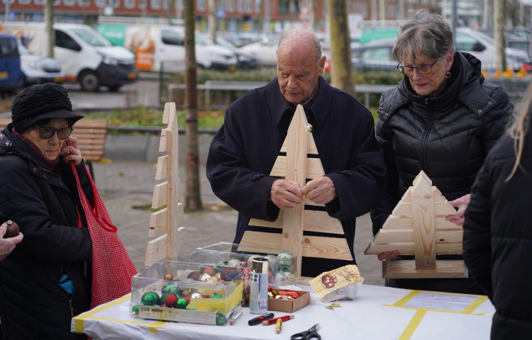 Bewoners versieren kerstboom bij de oliebolleactie in Ypenburg