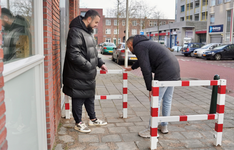 Twee mannen op straat aan het kijken naar een rood met wit hekje.