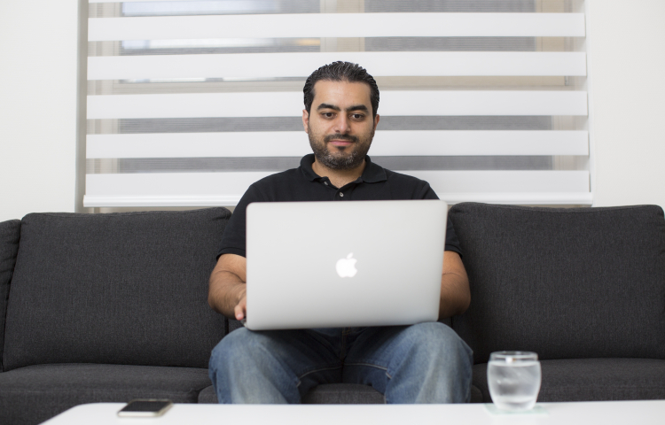 Man zit op de bank met laptop op schoot