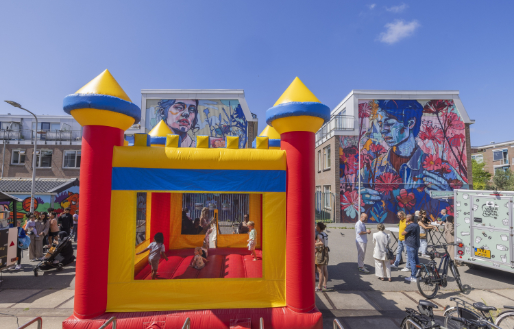 Een springkussen met daarop kinderen en eromheen volwassenen