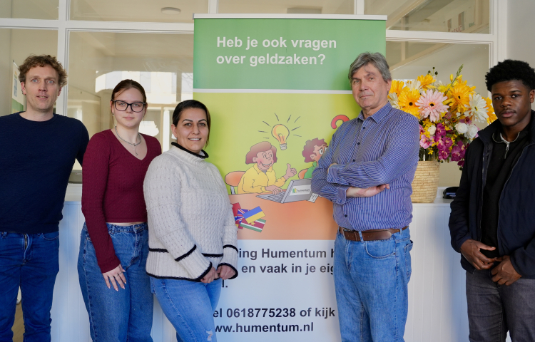 Vijf mensen van Humentum poseren bij een banner