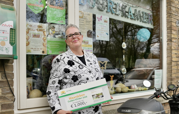 Lydia poseert voor haar Buurtkamer met de cheque van de Gulden Klinker.