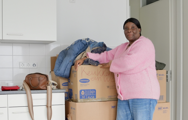 Mevrouw de Lannoy in haar nieuwe huis. Ze staat voor een stapel verhuisdozen.