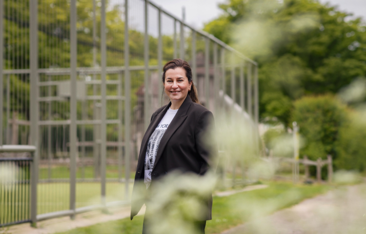 Zulehya poseert voor de camera, lacht en staat voor een voetbalveld