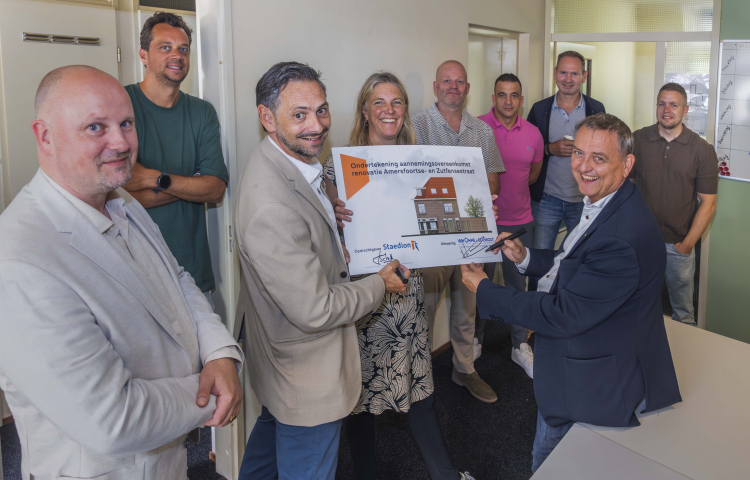 Kay Schellen en Olaf Lange ondertekenen een bord met daarop een afbeelding van het wooncomplex