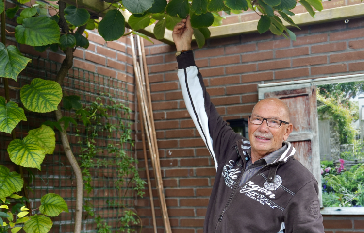 Henk staat in zijn tuin en laat zijn planten zien