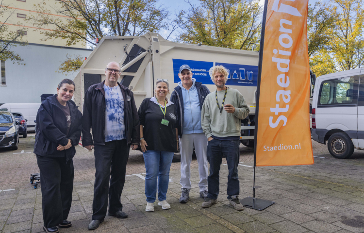 Collega's staan naast vlag voor vuilniswagen