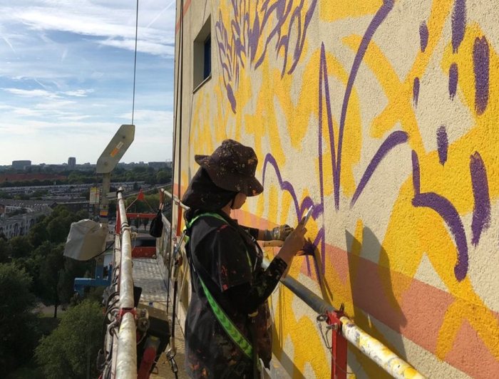 Kunstenaar Gleo is aan het werk aan de muurschildering