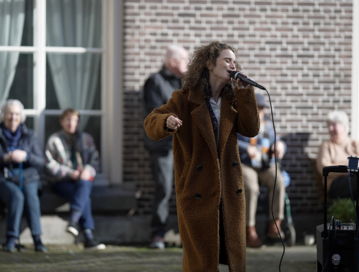 Zangeres zingend op een plein met kijkende mensen